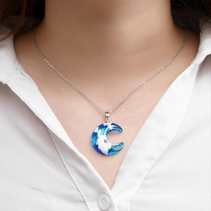 "Damhalsband i harts med blå himmel och vita moln, hjärtformad design, justerbar guldkedja 45 cm, elegant accessoar."