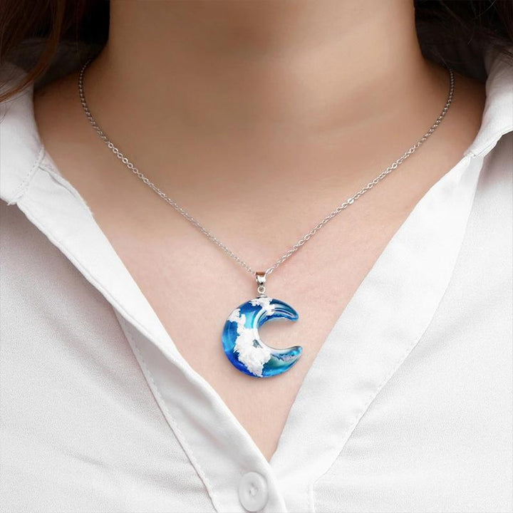 "Damhalsband i harts med blå himmel och vita moln, hjärtformad design, justerbar guldkedja 45 cm, elegant accessoar."