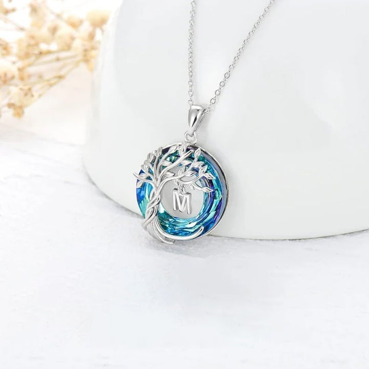 "Damhalsband i silver med livets träd och blå kristall, eleganta och symboliska smycken för unik kvinnlig stil."