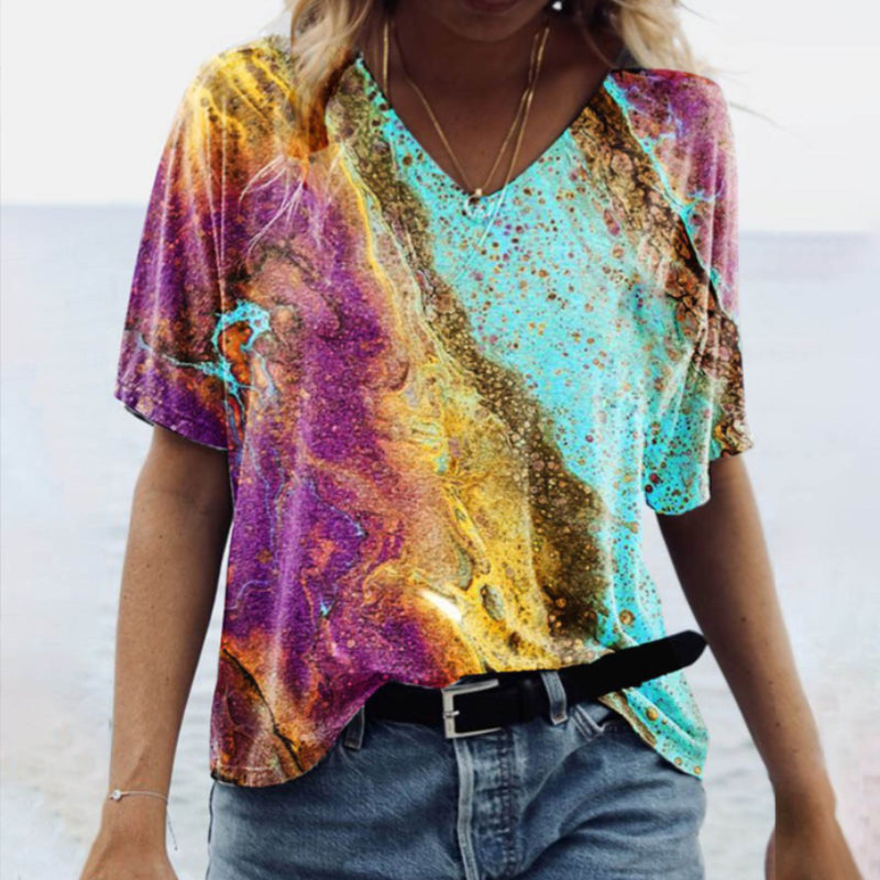 "Damtopp med sommarmarmortryck, V-ringning och utsvängd fåll, perfekt för stranddagar och vardagslook."