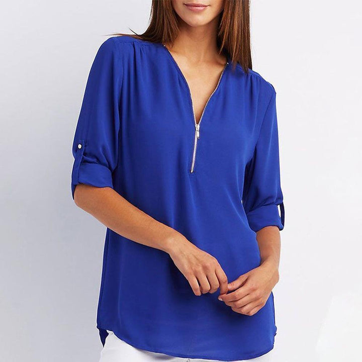 "Elegant damblusa med V-ringning och justerbar dragkedja, finns i flera färger; perfekt för stil och komfort."