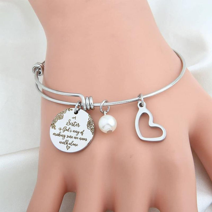 "Elegant justerbart syster charm armband i rostfritt stål, designat för damhandleder, med inspirerande text och hjärtsymbol."