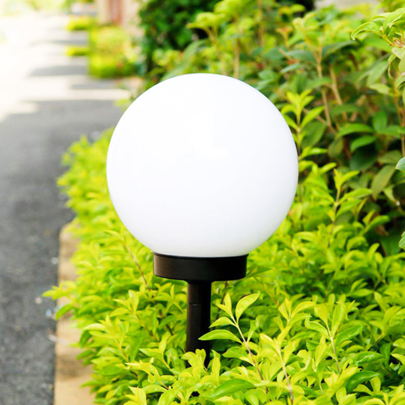 "Elegant LED-solcellslampa för gräsmatta med kulvit design, silverdetaljer och varm belysning för trädgårdar."