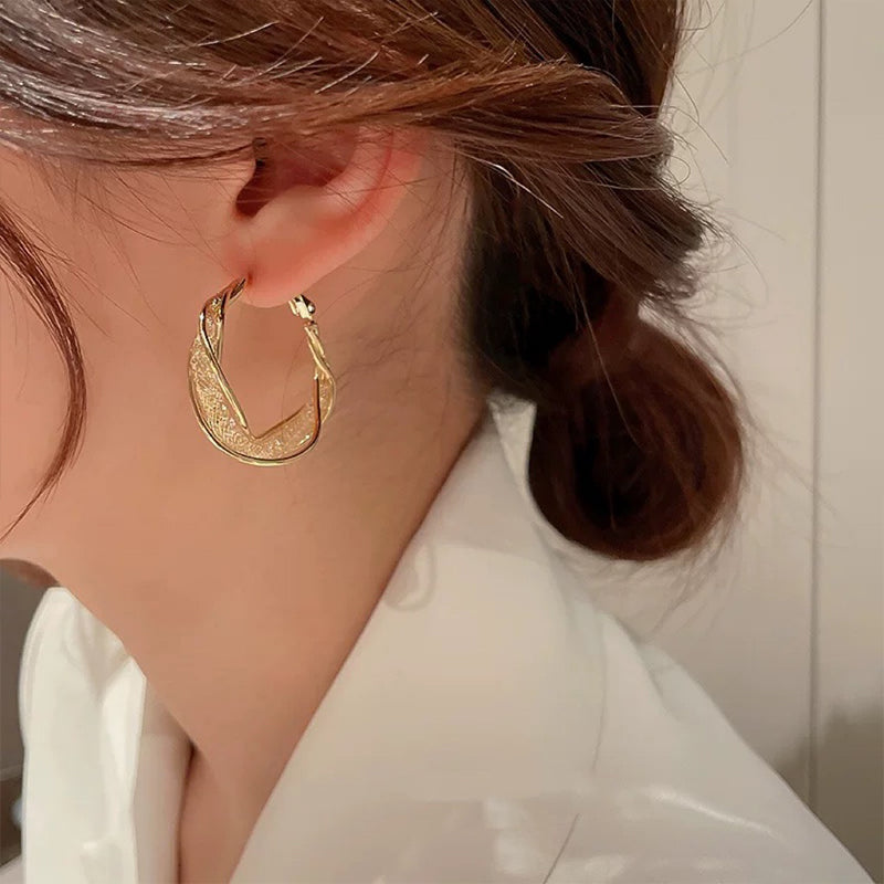 "Elegant twist örhängen för kvinnor i guld och silver, geometrisk design, perfekt accessoar för alla tillfällen."