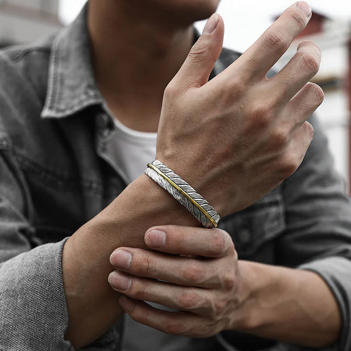 Elegant vintage fjäderarmband för damer i justerbart silver och guld, retro stil med symbolisk fjäderdetalj.