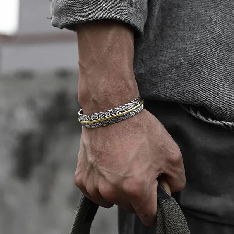 Elegant vintage fjäderarmband för damer i justerbart silver och guld, retro stil med symbolisk fjäderdetalj.