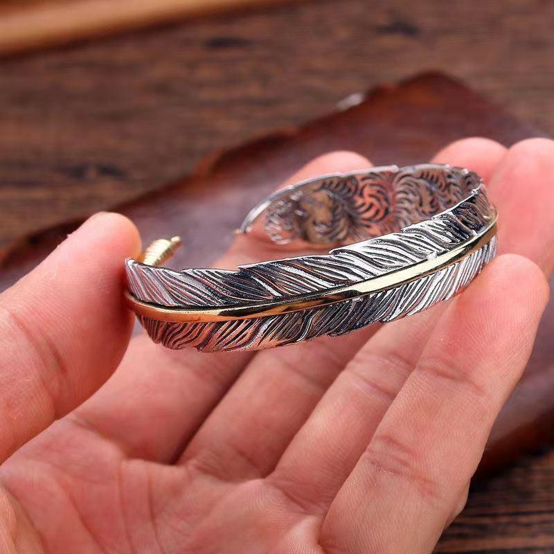 Elegant vintage fjäderarmband för damer i justerbart silver och guld, retro stil med symbolisk fjäderdetalj.