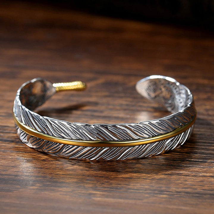Elegant vintage fjäderarmband för damer i justerbart silver och guld, retro stil med symbolisk fjäderdetalj.