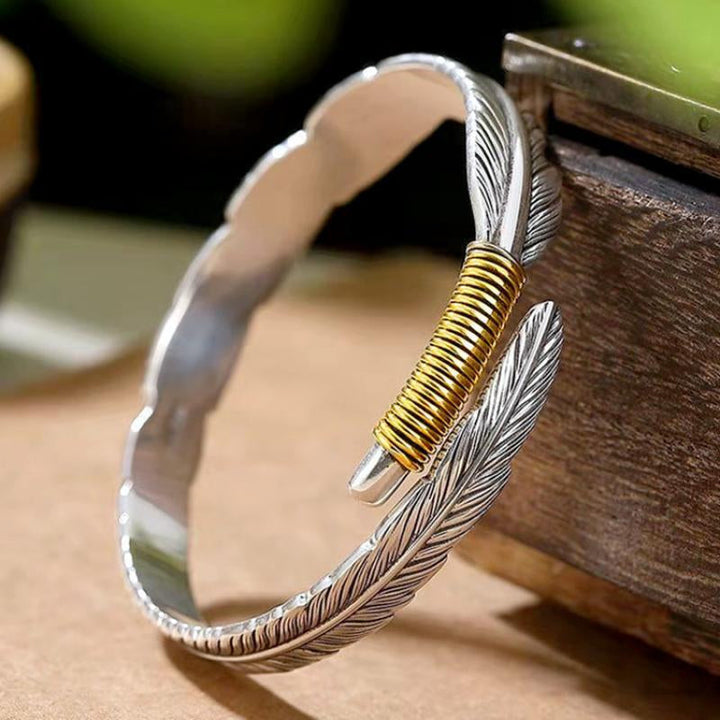 Elegant vintage fjäderarmband för damer i justerbart silver och guld, retro stil med symbolisk fjäderdetalj.