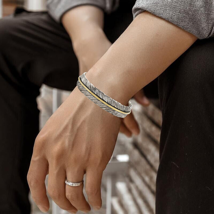 Elegant vintage fjäderarmband för damer i justerbart silver och guld, retro stil med symbolisk fjäderdetalj.