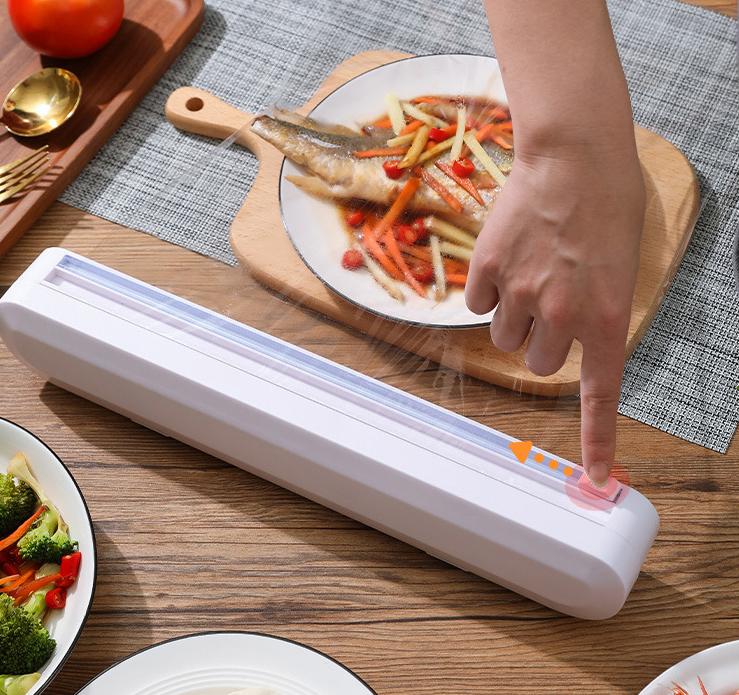 "Ergonomisk plastfolieskärare i vitt med magnetfäste, modern design, skär plast- och aluminiumfolie effektivt."