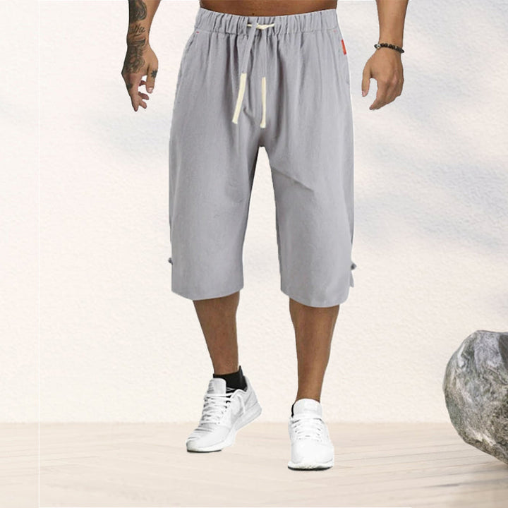 "Herrshorts i beige bomull-linne, dragsko och tre fickor, framifrån i soligt väder"