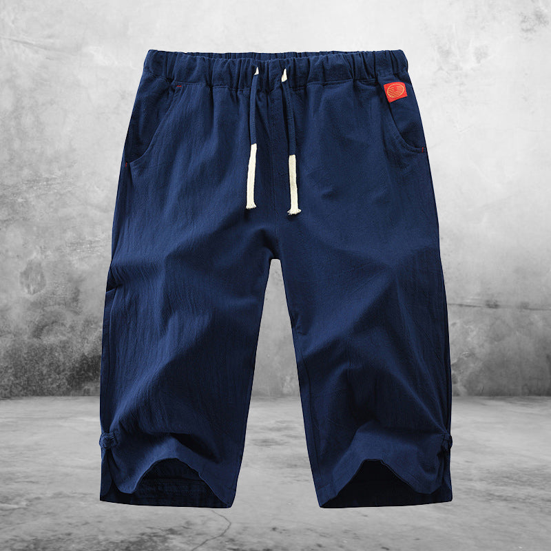 "Herrshorts i beige bomull-linne, dragsko och tre fickor, framifrån i soligt väder"