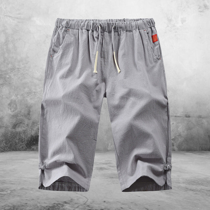 "Herrshorts i beige bomull-linne, dragsko och tre fickor, framifrån i soligt väder"