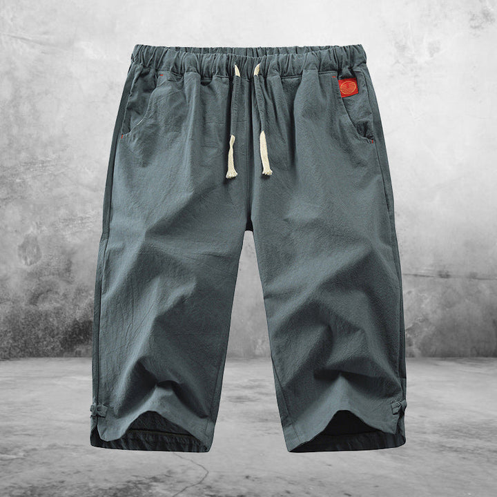 "Herrshorts i beige bomull-linne, dragsko och tre fickor, framifrån i soligt väder"