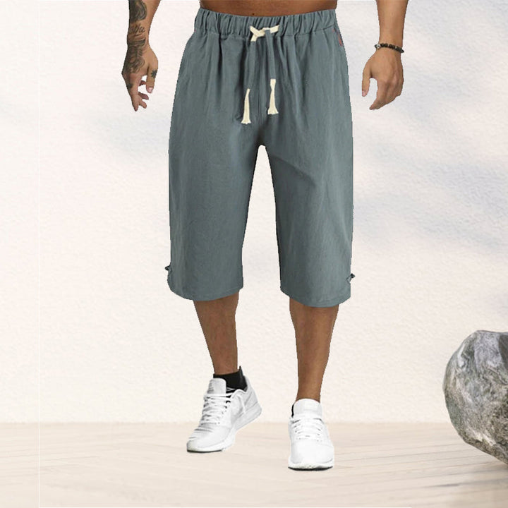 "Herrshorts i beige bomull-linne, dragsko och tre fickor, framifrån i soligt väder"