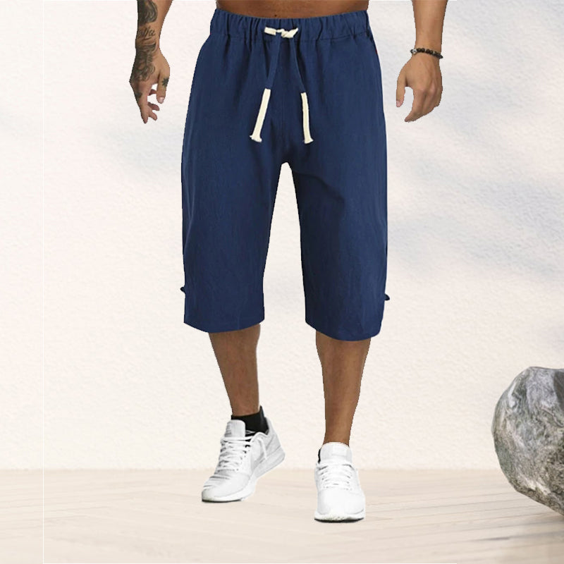 "Herrshorts i beige bomull-linne, dragsko och tre fickor, framifrån i soligt väder"