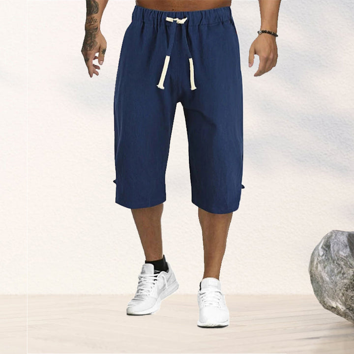 "Herrshorts i beige bomull-linne, dragsko och tre fickor, framifrån i soligt väder"