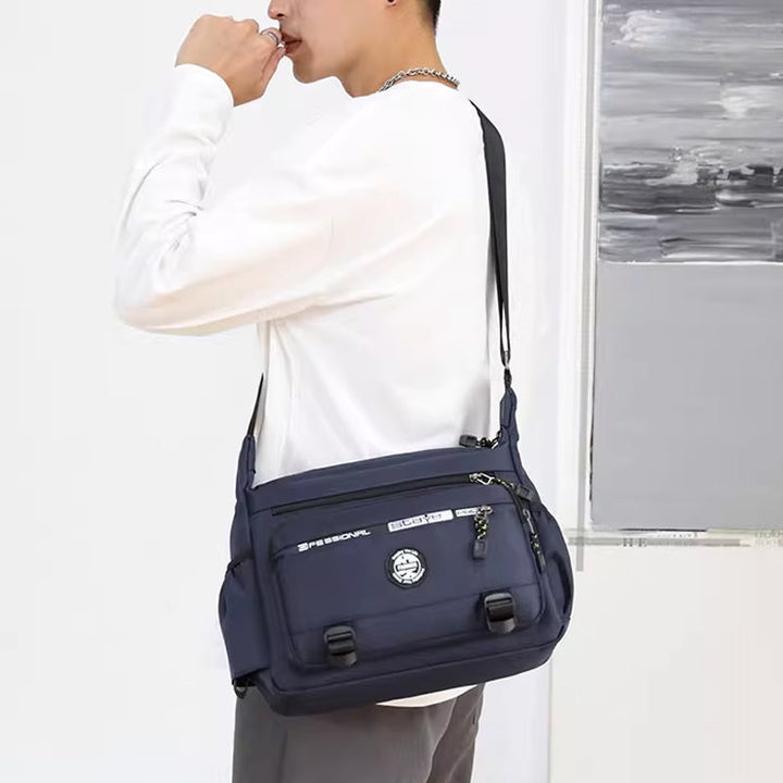 "Högkvalitativ svart axelväska för män med flera fickor, justerbara remmar och vattentät yta, sedd bakifrån."