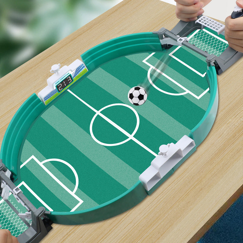 Interaktivt bordfotbollsspel för familjen, grön plast, närbild av planen och spelare, främjar motorik och samspel.