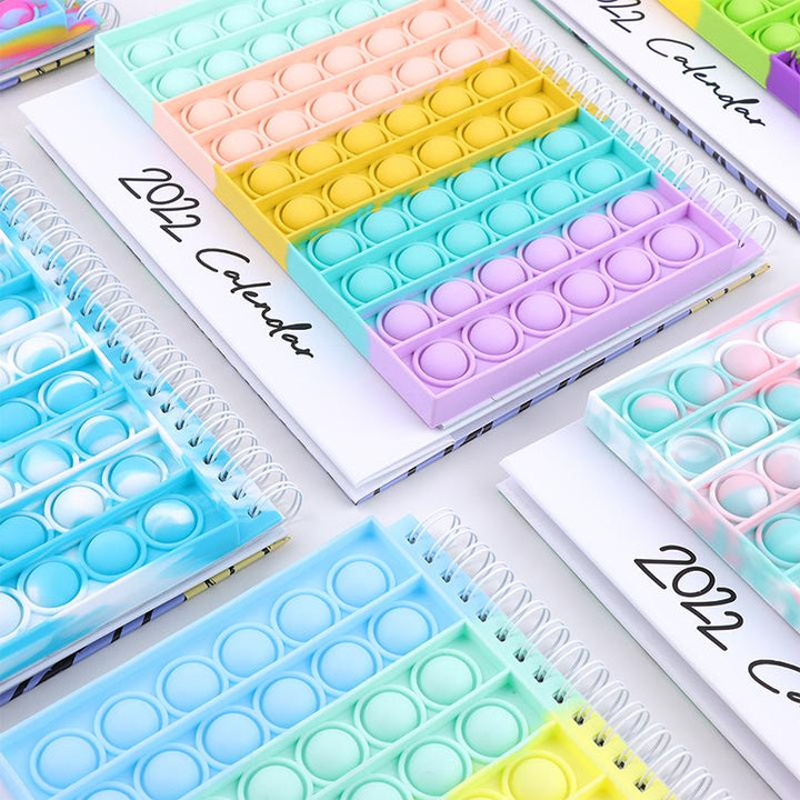 "Kalender med färgglada silikonbubblor för stresslindring och planering, perfekt för hem och kontor, i hållbart material."