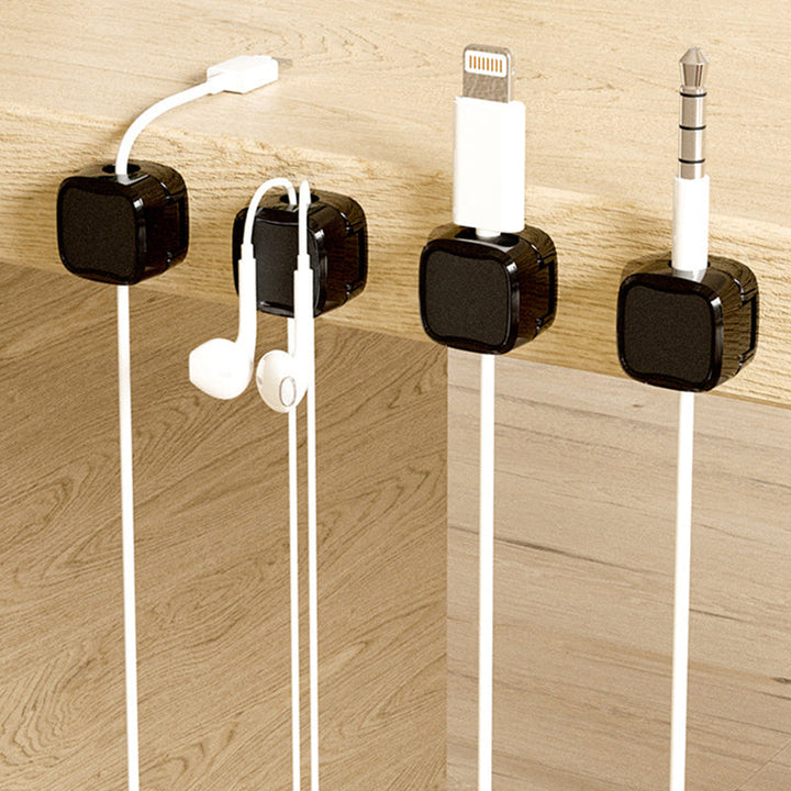 "Magnetisk kabelhållare håller kablar organiserade, stilren design i svart och vit, passar kablar upp till 7 mm."