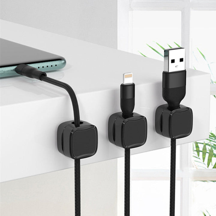 "Magnetisk kabelhållare håller kablar organiserade, stilren design i svart och vit, passar kablar upp till 7 mm."
