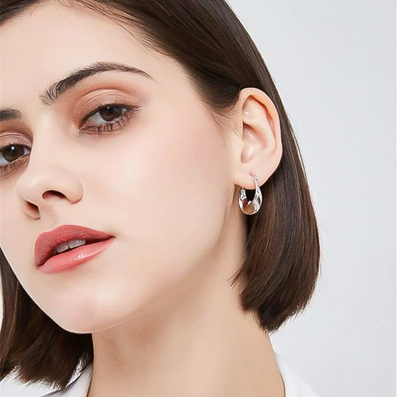 "Möbius-design guldfärgade örhängen för damer, elegant skulpturell stil med ljusreflekterande glans."