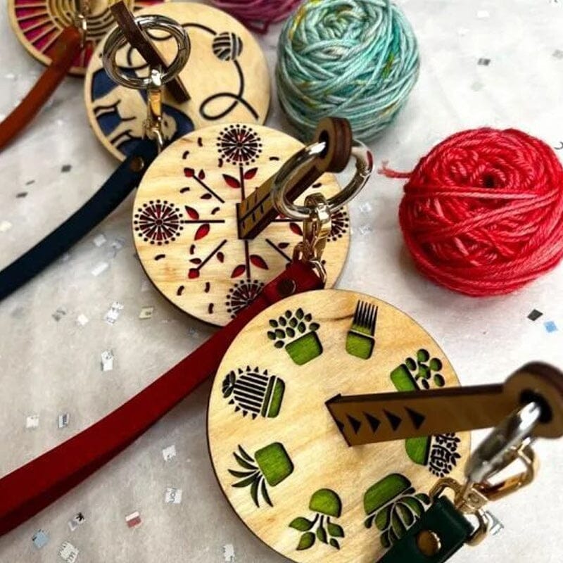 "Modern trähållare för garn i minimalistisk design, visar flera garnrullar i olika färger på en stabil träbas."