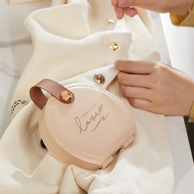 "Multifunktionell handhållen sömnadssats i beige och grön med nålar och trådar i en kompakt, lätt design."