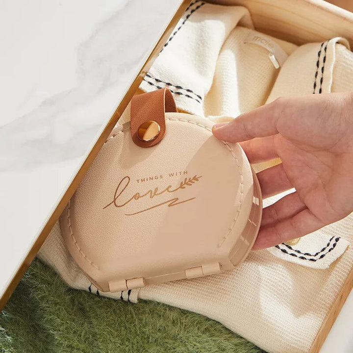 "Multifunktionell handhållen sömnadssats i beige och grön med nålar och trådar i en kompakt, lätt design."