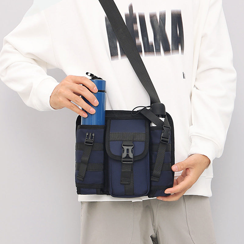 Unisex crossbody axelväska i tåligt tyg, grå. Framifrån med dragkedjor och justerbar rem, perfekt för organiserad förvaring.