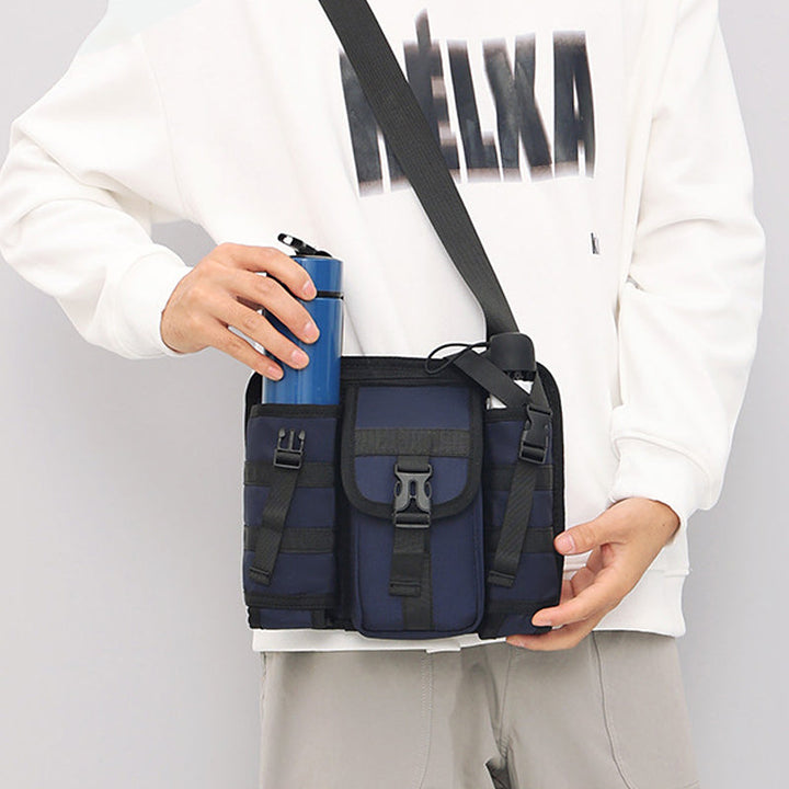 Unisex crossbody axelväska i tåligt tyg, grå. Framifrån med dragkedjor och justerbar rem, perfekt för organiserad förvaring.